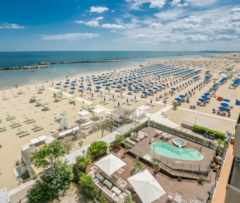 Spiaggia con ombrelloni colorati e piscina vista mare.