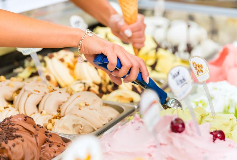 Mani servono gelato colorato, coni in sottofondo, atmosfera di dolcezza e freschezza.